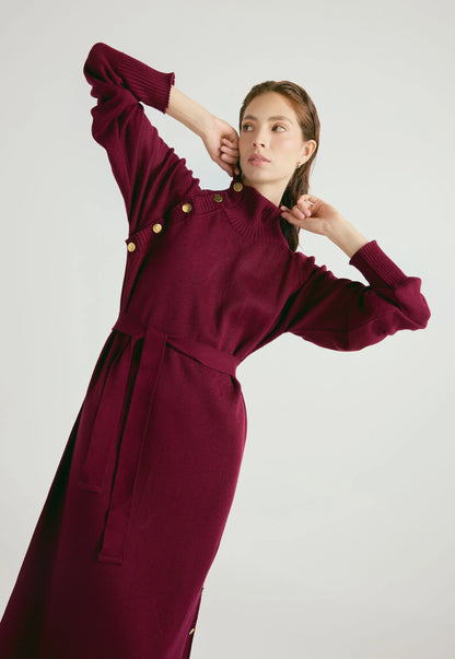 Vestido Danielle largo para mujer con cuello alto, botones dorados, cinturón ajustable y abertura en la falda, en tejido de punto cerrado.
