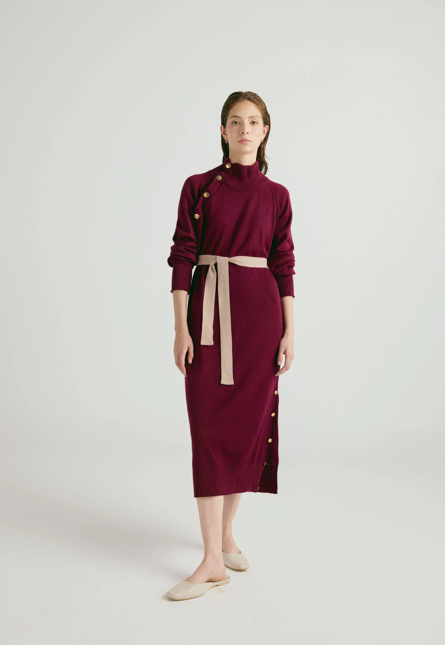 Vestido Danielle largo para mujer con cuello alto, botones dorados, cinturón ajustable y abertura en la falda, en tejido de punto cerrado.
